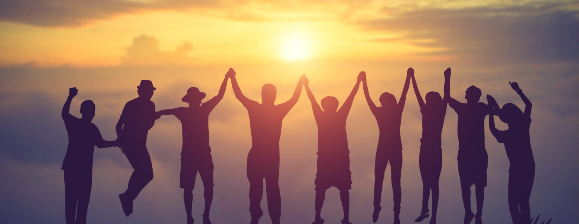 groupe de jeune saute main dans la main devant un couché de soleil
