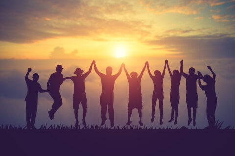 groupe de jeune saute main dans la main devant un couché de soleil